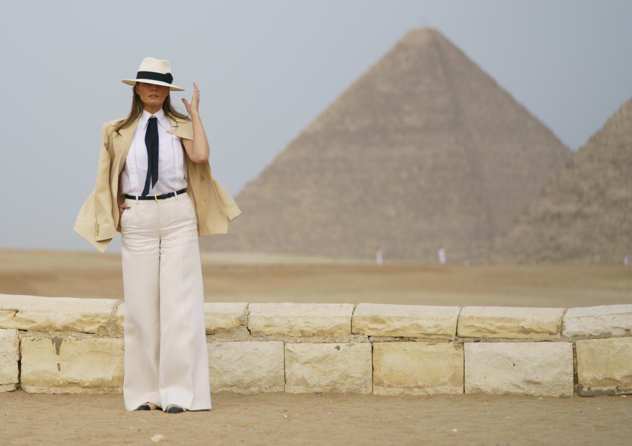 First lady Melania Trump reaches for her hat as she pauses for media during a visit to the historical Giza Pyramids site near Cairo, Egypt on Saturday, Oct. 6, 2018. Trump is visiting Africa on her first big solo international trip. (AP Photo/Carolyn Kaster)