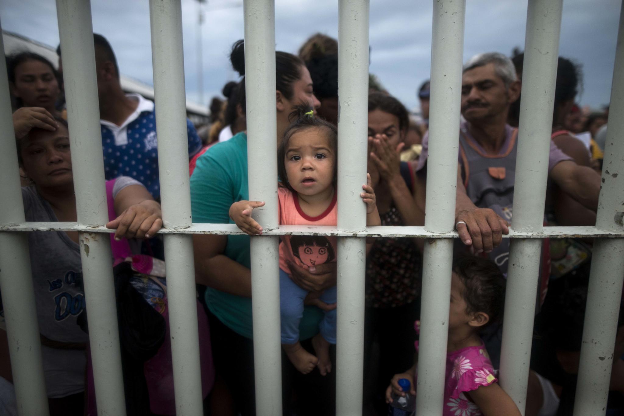 Migrants bound for the U.S.-Mexico border wait on a bridge that stretches over the Suchiate River, connecting Guatemala and Mexico, in Tecun Uman, Guatemala, Friday, Oct. 19, 2018.  The gated entry into Mexico via the bridge has been closed.  The U.S. president has made it clear to Mexico that he is monitoring its response. On Thursday he threatened to close the U.S. border if Mexico didn't stop the caravan. (AP Photo/Oliver de Ros)